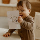 bébé qui tient une carte étape tapilou x babyatoutprix dans les mains