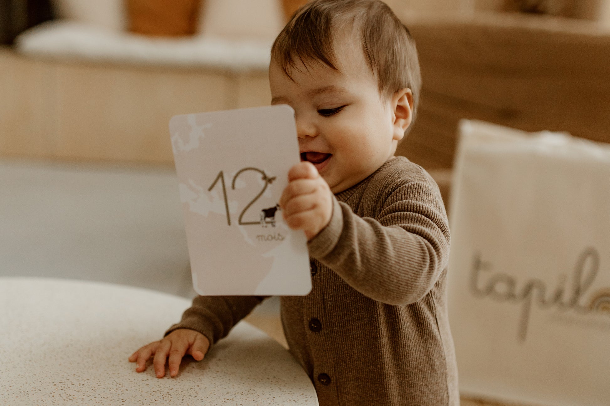 bébé qui tient une carte étape tapilou x babyatoutprix dans les mains