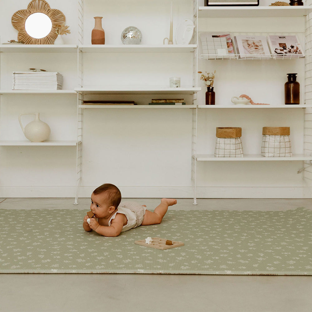bébé sur le tapis de jeu xl avec des motifs fleurs